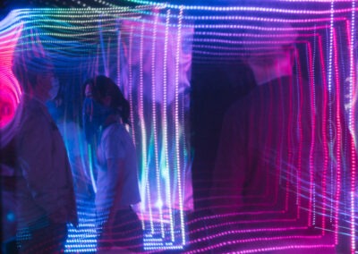 an and woman stood in Simon Kilmister's brainbox surrounded by blue and pink square lights